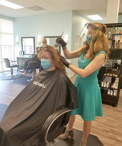 Studio B owner and master stylist Bethany Yurachek applies color to a customer’s hair, both wearing personal protection equipment.