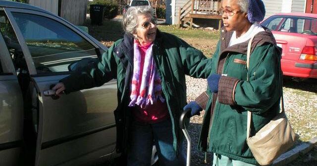 Shepherd's Center volunteer assisting a client to the car to give her a ride to an appointment.
